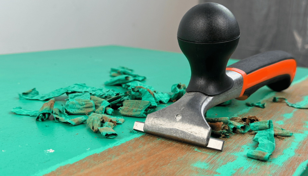 carbide scraper removing bright teal paint on coffee table